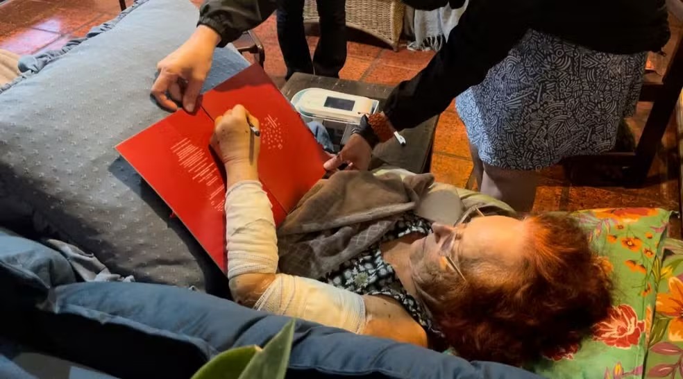 Escritora Roseana Murray dá autógrafos com a mão esquerda após deixar hospital